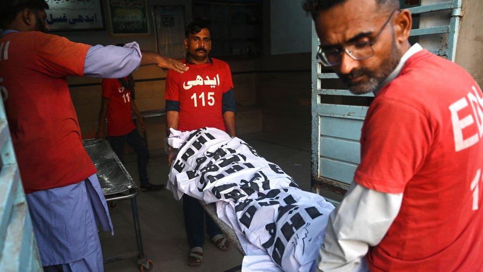 Volunteers carry a wrapped dead body