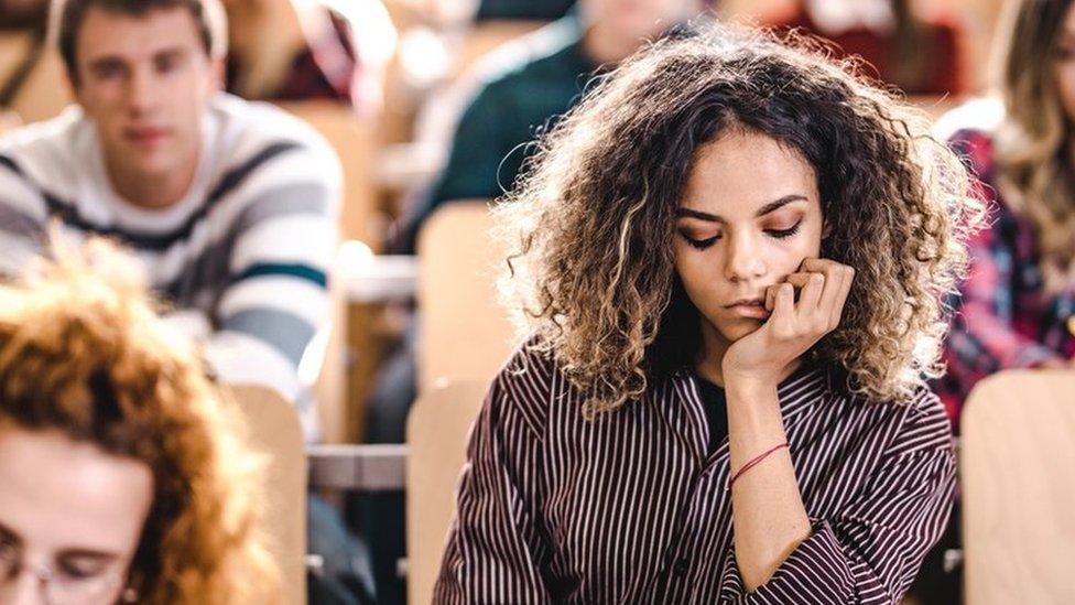 Female college student feeling sad on a class at lecture hall.