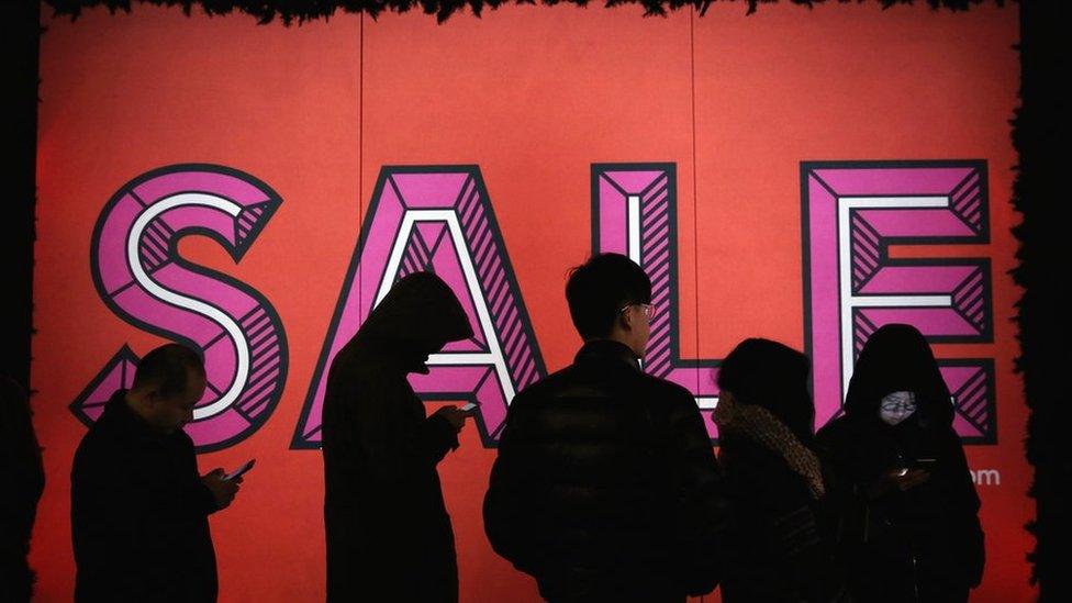 Shoppers standing outside a store front