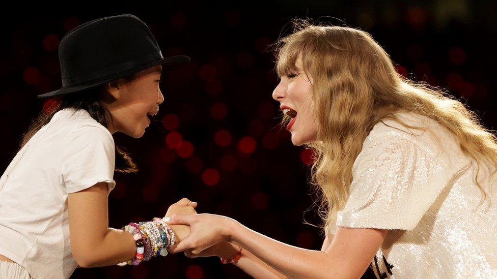 Young fan joins Taylor on Stage.