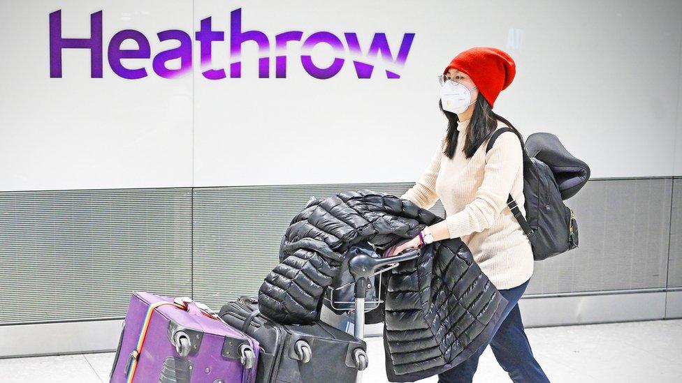 woman-walking-through-heathrow-airport-wearing-face-mask