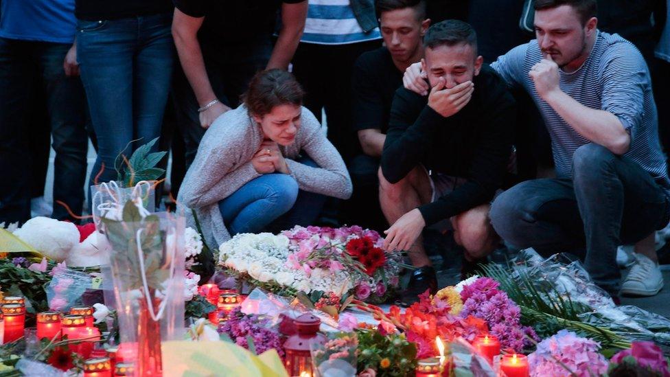 People mourn near the crime scene at OEZ shopping center the day after a shooting spree left nine victims dead on July 23, 2016 in Munich,