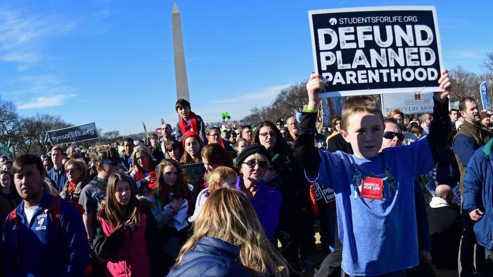 Kid holds 'defund planned parenthood' sign