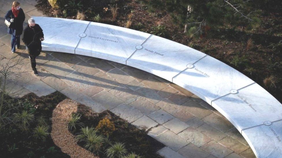 People walk around the Glade of Light memorial