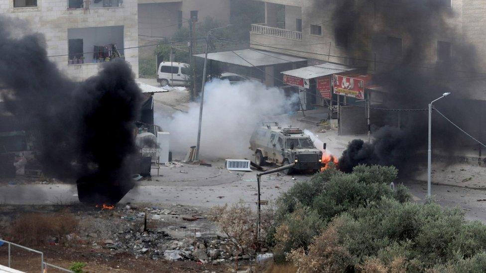 An explosive charge detonates near an Israeli armoured vehicle during an Israeli military raid in the West Bank city of Jenin (19 June 2023)