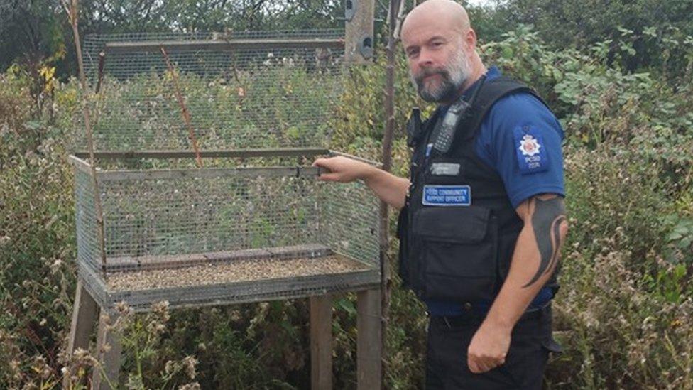 An officer with finch trap