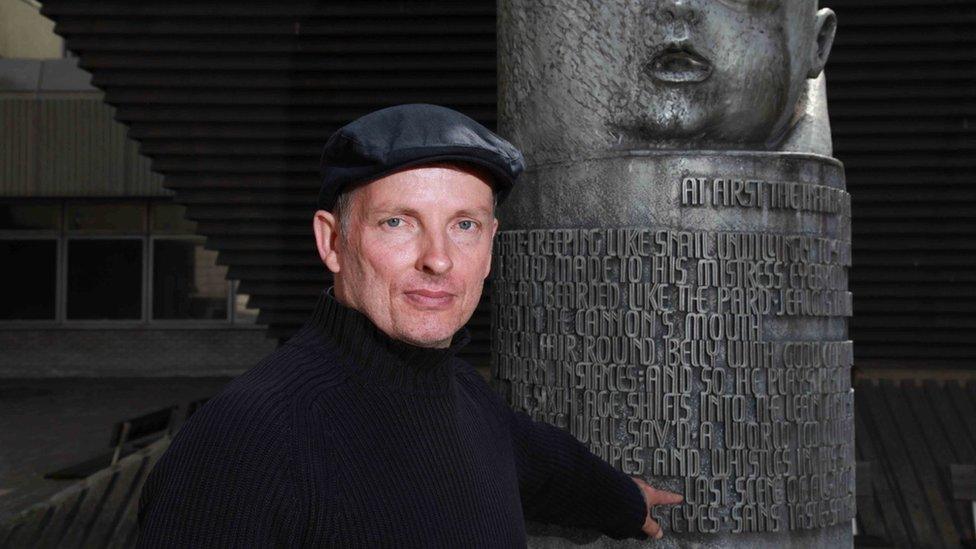 Declan McHugh pointing to verses from Shakespeare's As You Like It on The Seven Ages of Man sculpture in Queen Victoria Street, Blackfriars