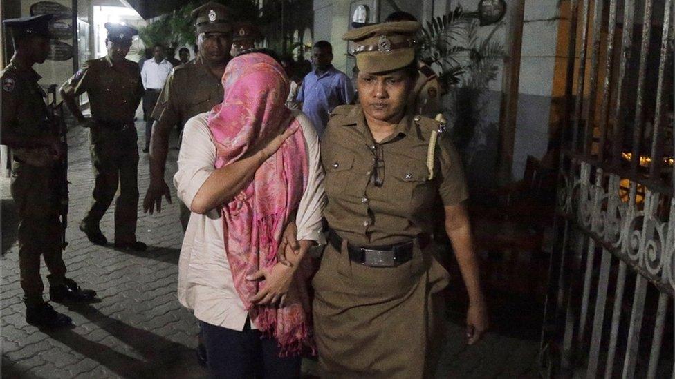 The employee of the Swiss embassy in Sri Lanka (head covered) is escorted by a police officer in Colombo on 16 December 2019