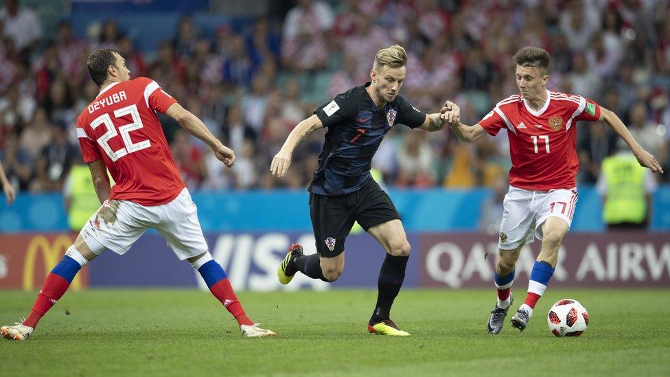 Ivan Rakitić running past two defenders.