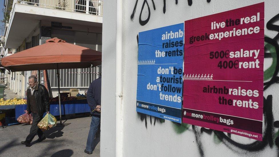 A man walks past posters against Airbnb in a working class district of Athens