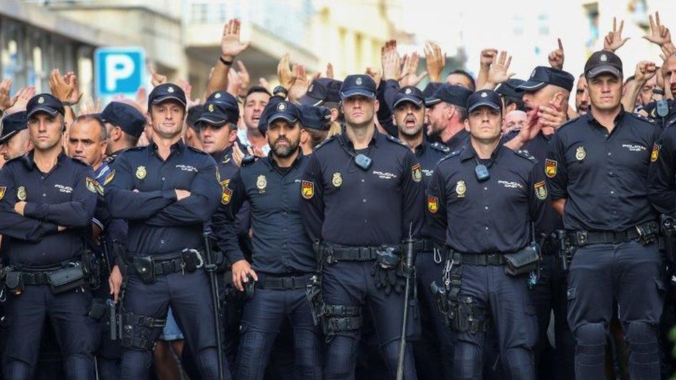 Spanish National Police officers stand outside their hotel as they face locals protesting against their presence in Pineda de Mar, north of Barcelona (03 October 2017)