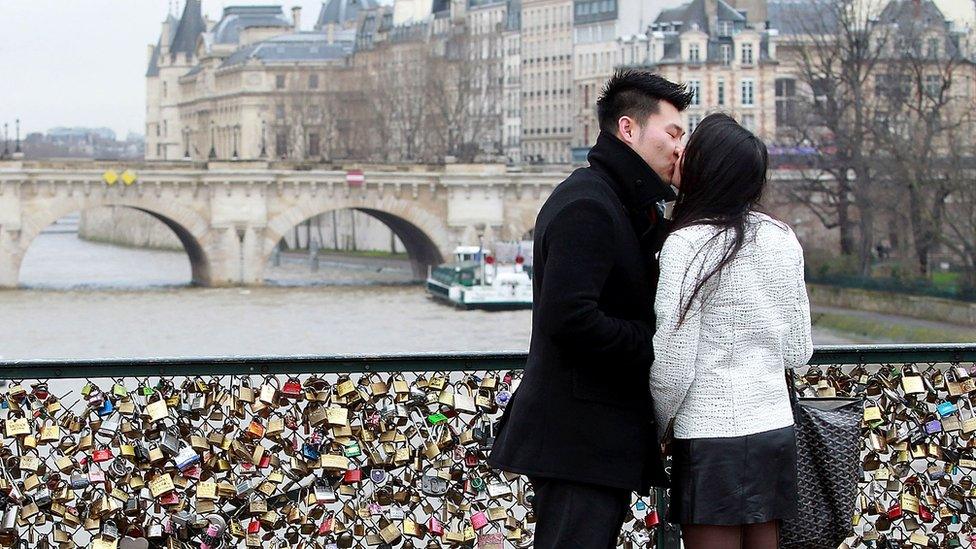 young couple kiss on a bridge