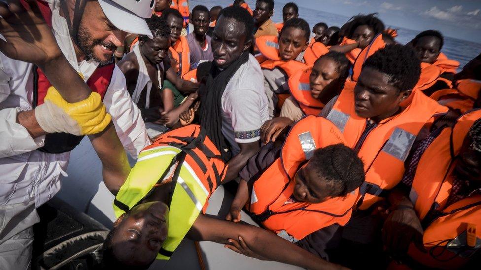 A member of Medecins Sans Frontieres carries a young migrant aboard a rescue vessel during an operation off the coast of Libya