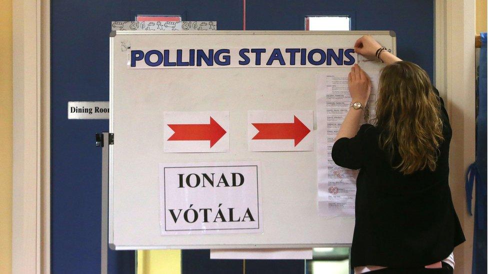 A returning officer adjusts a sign at a polling station in Castlebar, County Mayo, as voters go to the polls all around the state on Friday