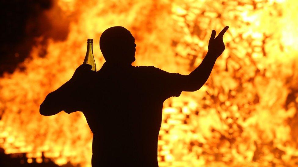 A man dances near a bonfire at Hopewell Square in Belfast's Shankill area