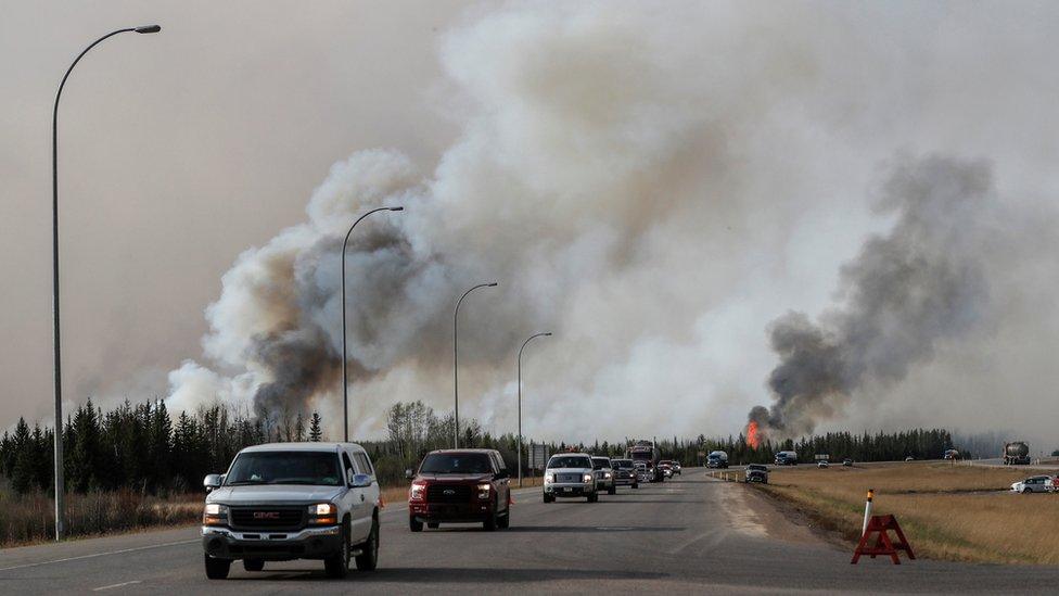 A convoy drives past wildfire in Canada