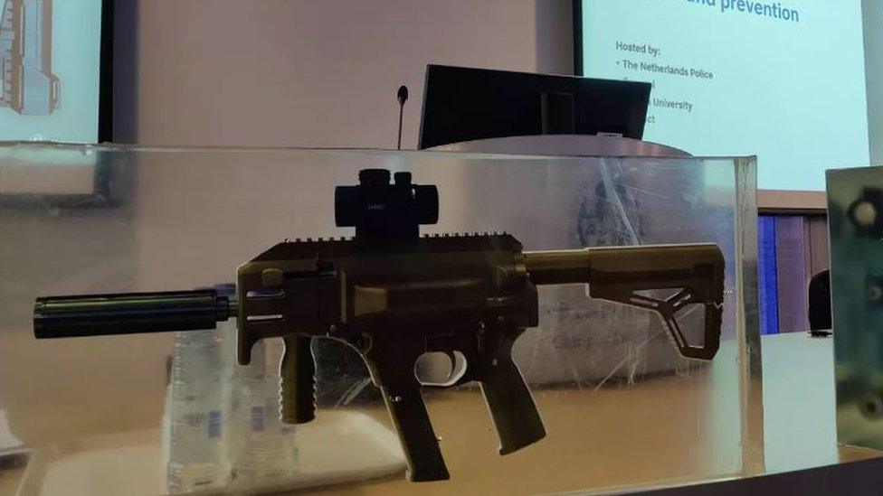 A picture of a Europol conference - a 3d printed gun is prominently displayed