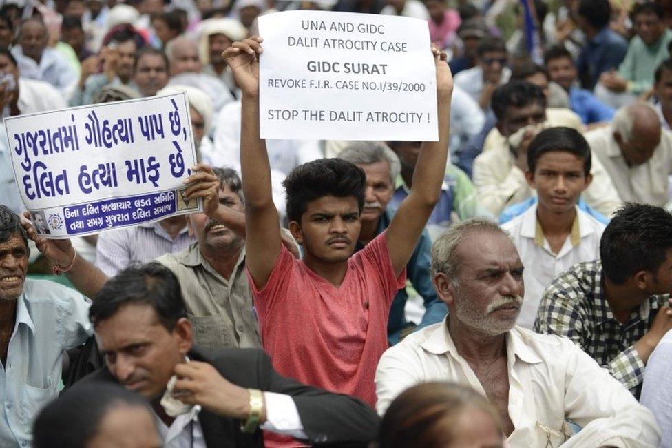 An Indian member of the Dalit caste community holds a placard saying "In Gujarat, Cow Slaughter is a Sin while Killing Dalits is pardonable" (L) as he participates in a protest rally against an attack on Dalit caste members in the Gujarat town of Una, in Ahmedabad on July 31, 2016.