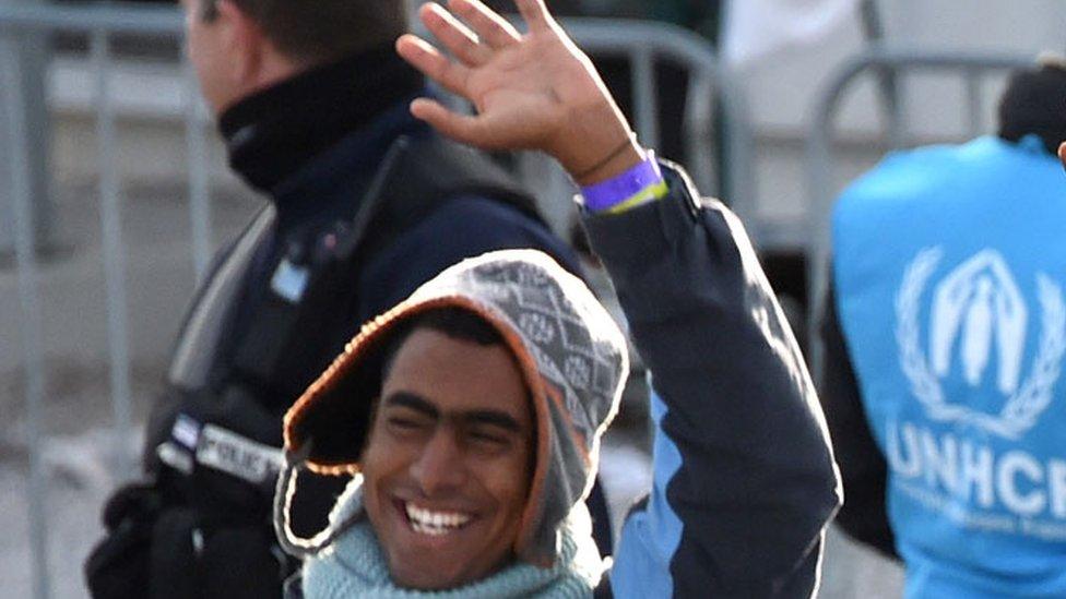 Migrants board a bus after leaving the camp