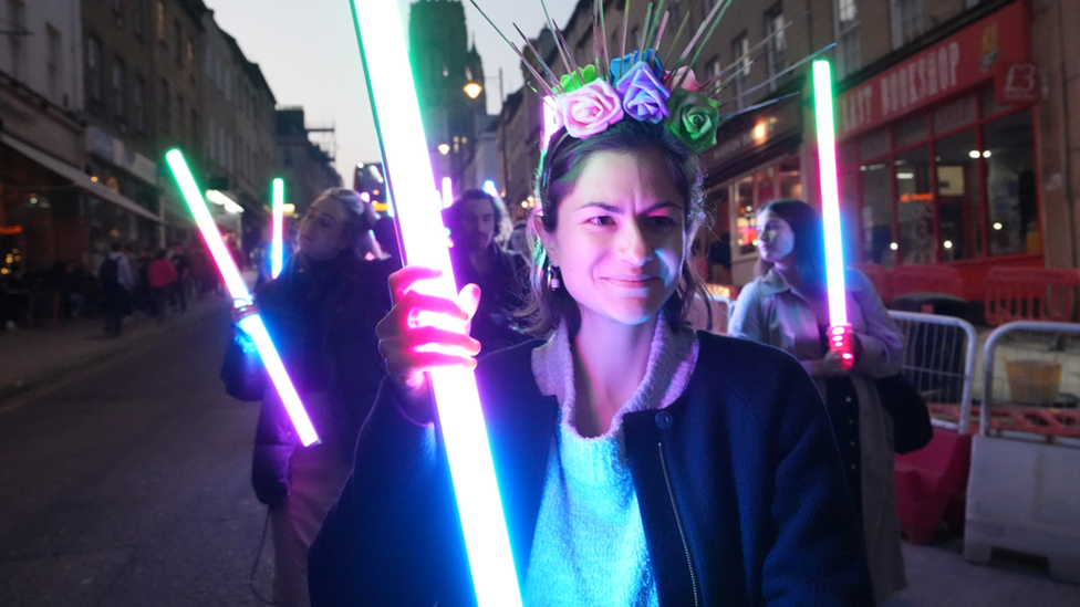 Woman holding illuminated pole