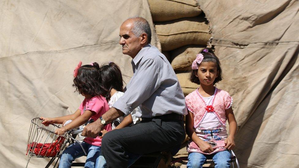 A Syrian man carries three girls on a bicycle in the northeastern Syrian city of Qamishli on September 13, 2016 as a truce brokered by Russia and the United States saw guns fall silent at sundown the previous night