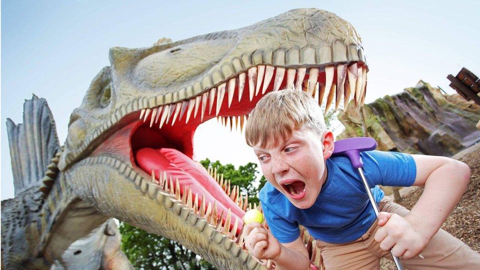 An animatronic dinosaur and a child at Mighty Claws Adventure Golf in Bournemouth