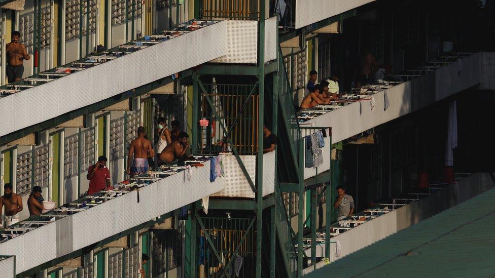 Migrant workers are pictured standing outside their dormitory rooms at Cochrane Lodge II