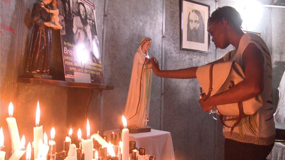 A believer touches a statue of the Virgin Mary and closes her eyes in prayer