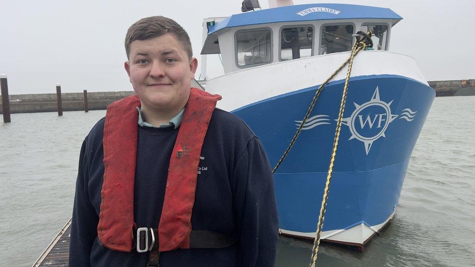 Alex Wightman standing in front of his boat, the Emma Claire