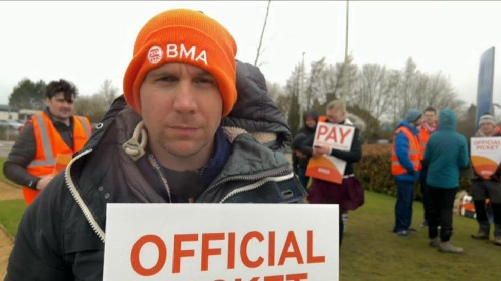 A man in a orange hat at a picket line