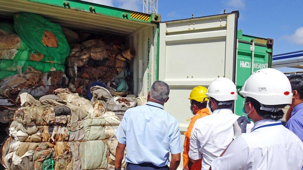 In this handout picture provided by Sri Lankan Customs on July 23, 2019, customs officials inspect the load of a container at a port in Colombo.