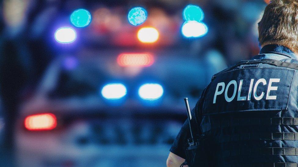 A police officer stands next to a marked vehicle