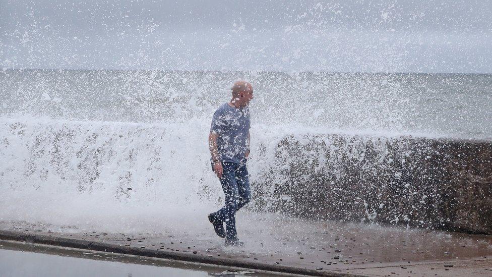 Waves crash over wall