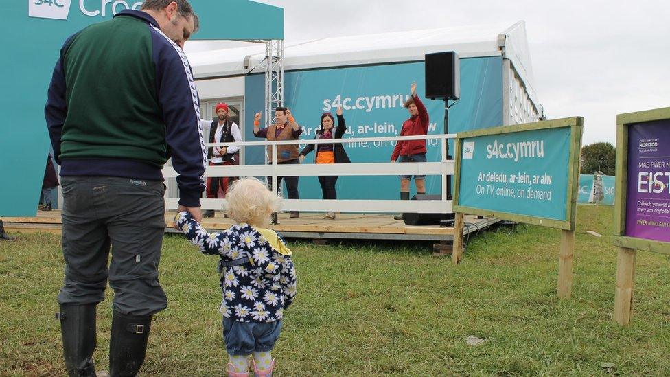 Criw Cyw yn rhoi gwên ar wynebau er gwaetha'r cymylau fore Mawrth. // A wave from S4C's 'Cyw' presenters makes this little lady's day.