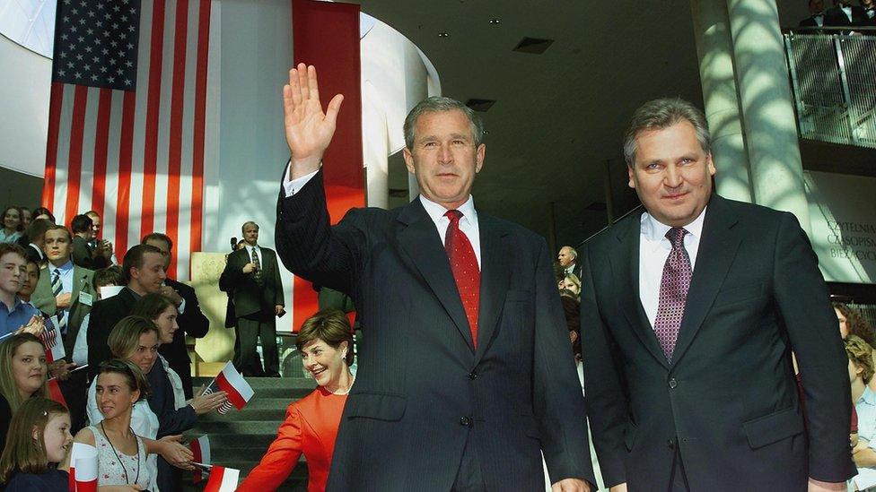 S President George W. Bush (C) waves as he stands next to Polish President Aleksander Kwasniewski(Rt), as Laura Bush greets the crowd to the rear shortly before President Bush delivered a major foreign policy speech on his administration's policies toward Europe at the Universtiy Library 15 June, 2001 in Warsaw, Poland