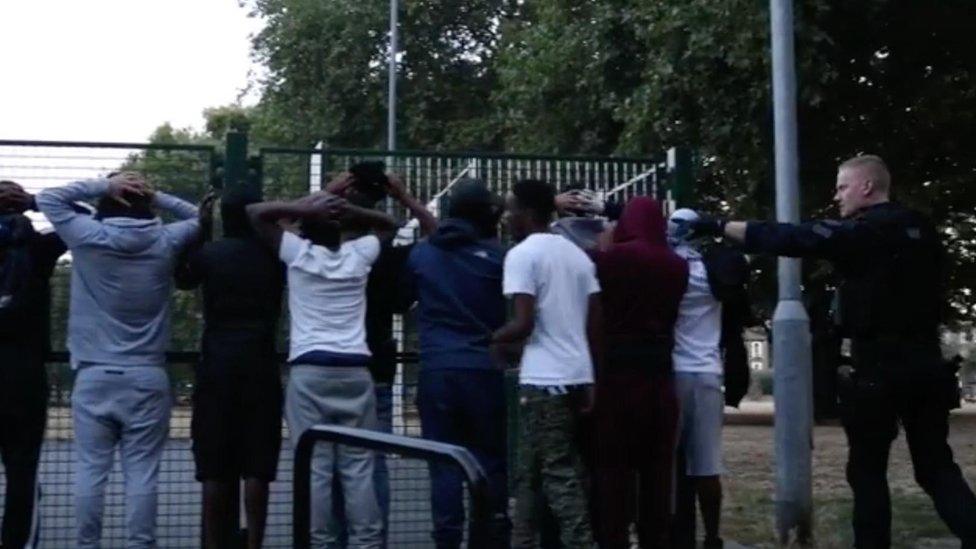 A group being stopped by armed police