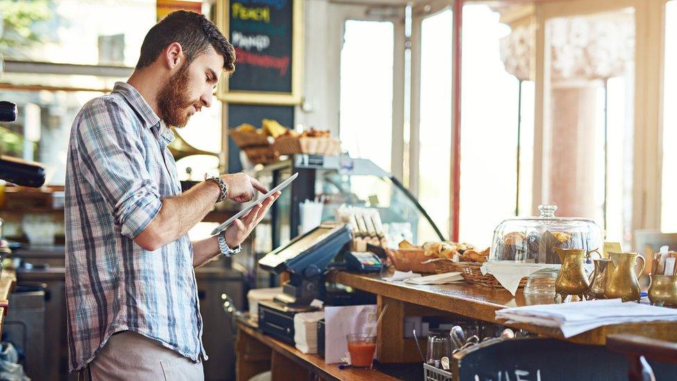 Young man using his phone in a coffee shop.