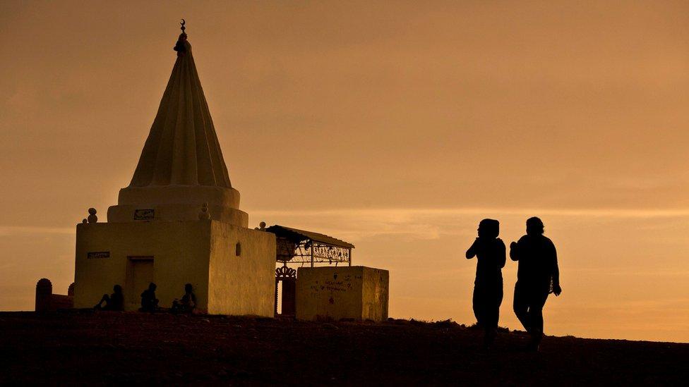 The sun sets as women visit a Yazidi shrine overlooking at Kankhe Camp for the internally displaced in Dohuk, northern Iraq (18 May 2016)