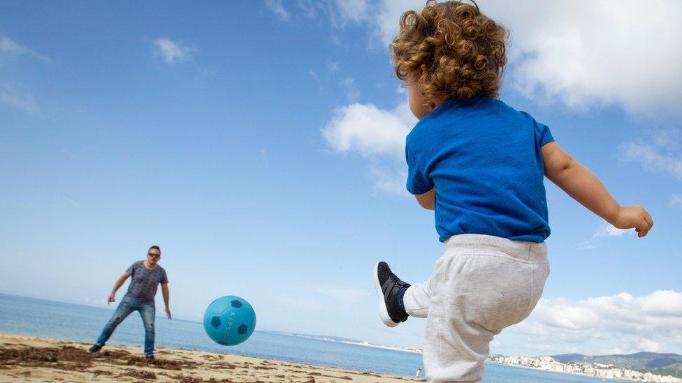 A child plays football with his father at Can Pere Antoni Beach in Palma de Mallorca, on April 26, 2020 during a national lockdown to prevent the spread of the COVID-19 disease.