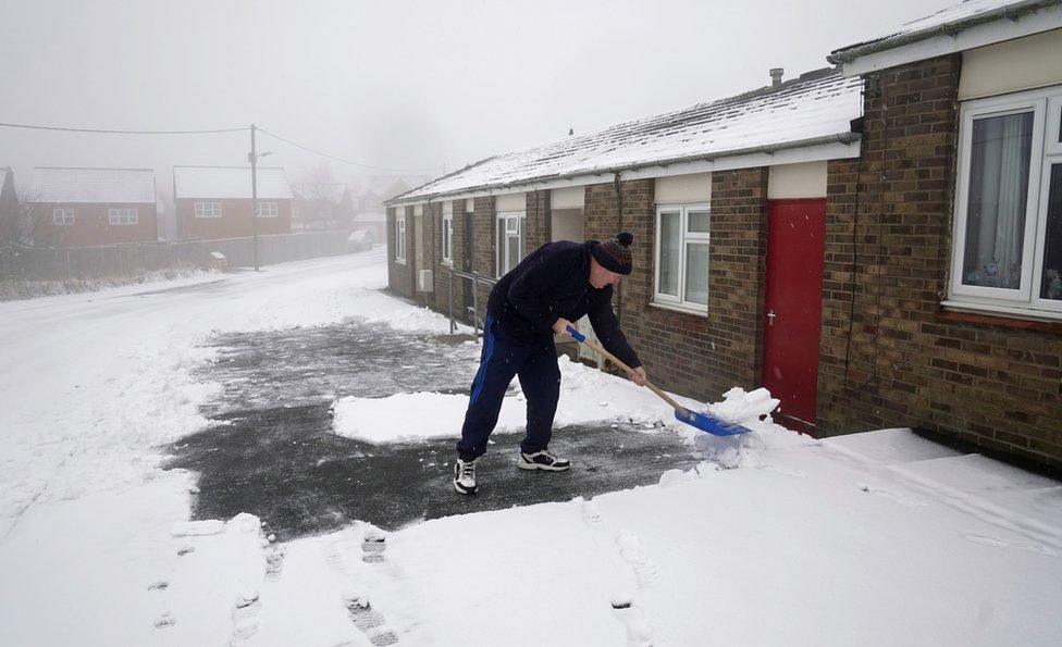 A man clears snow from the drive of his home in Tow Law, County Durham.