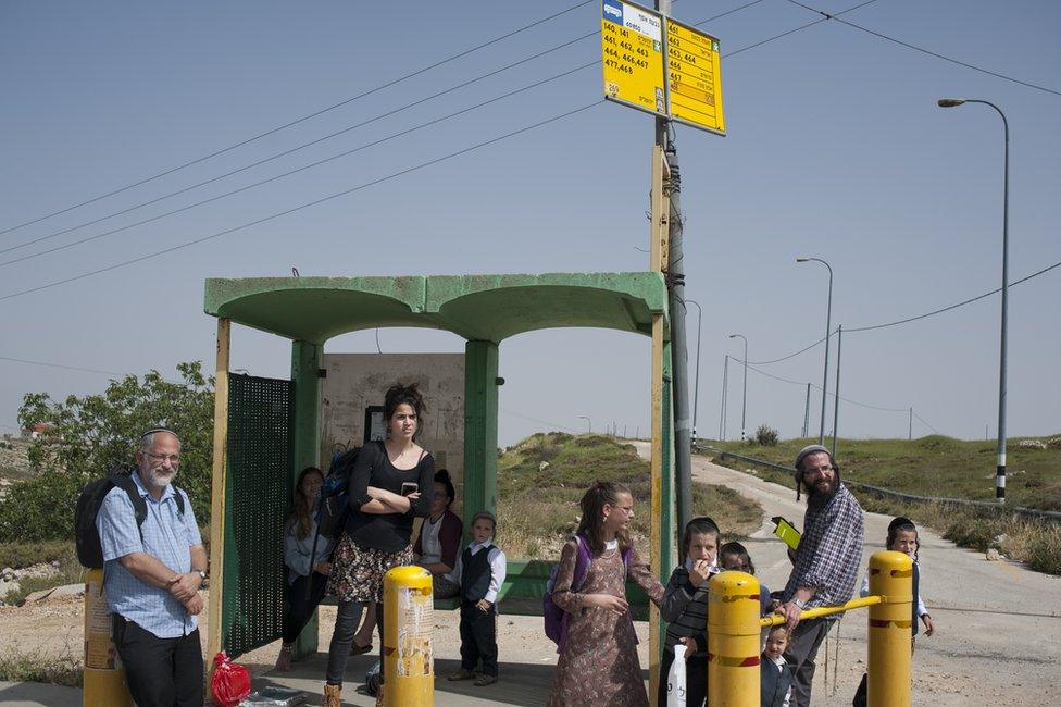 Hitchhikers standing by a road in the West Bank