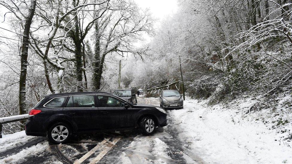 A car turns around after a fallen tree blocks the A40 near Sennybridge, Wales