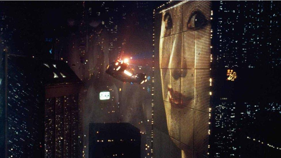 Still from Blade Runner film showing giant advert of Asian woman