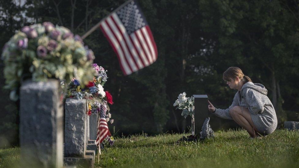 A woman mourns at a gravestone in Austin, Indiana