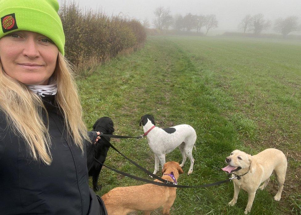 Woman in a field with three dogs