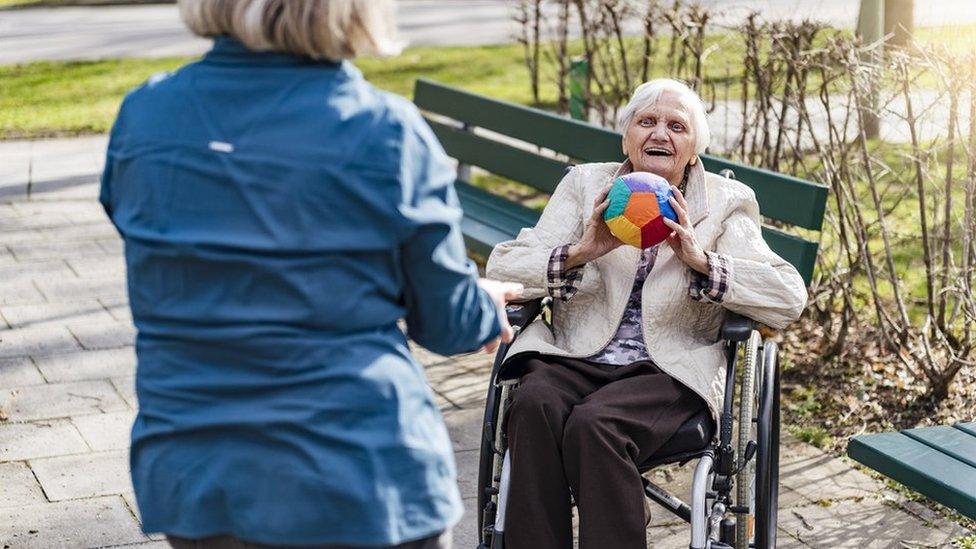 Care home resident throwing ball outdoors