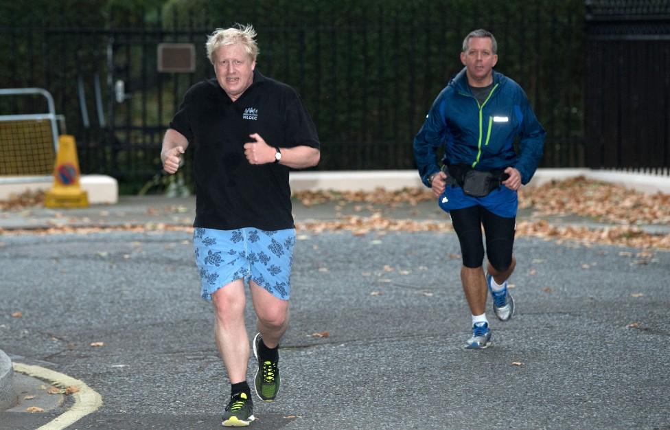 Boris Johnson goes for a jog with a close protection officer seen in the background