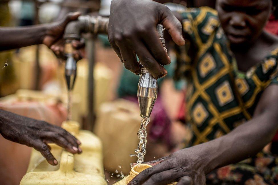 A woman draws water from a tap in Rhino camp, where tanks must be refilled up to three times a day