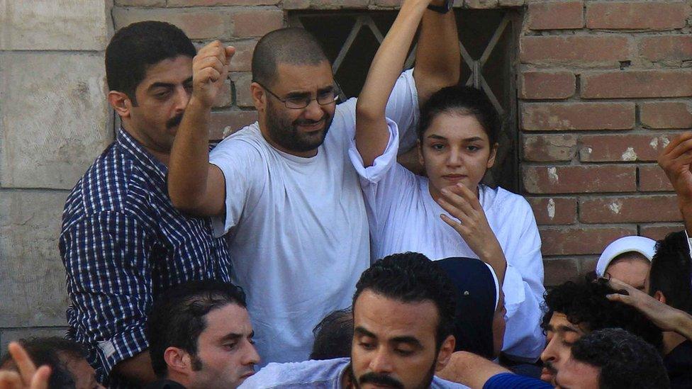 Sanaa Seif (R) and Alaa Abdel Fattah (C) raise their hands after being released from prison for the funeral of their father (28 August 2014)