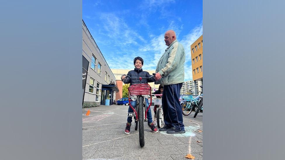 Milan on a bike with his father beside him